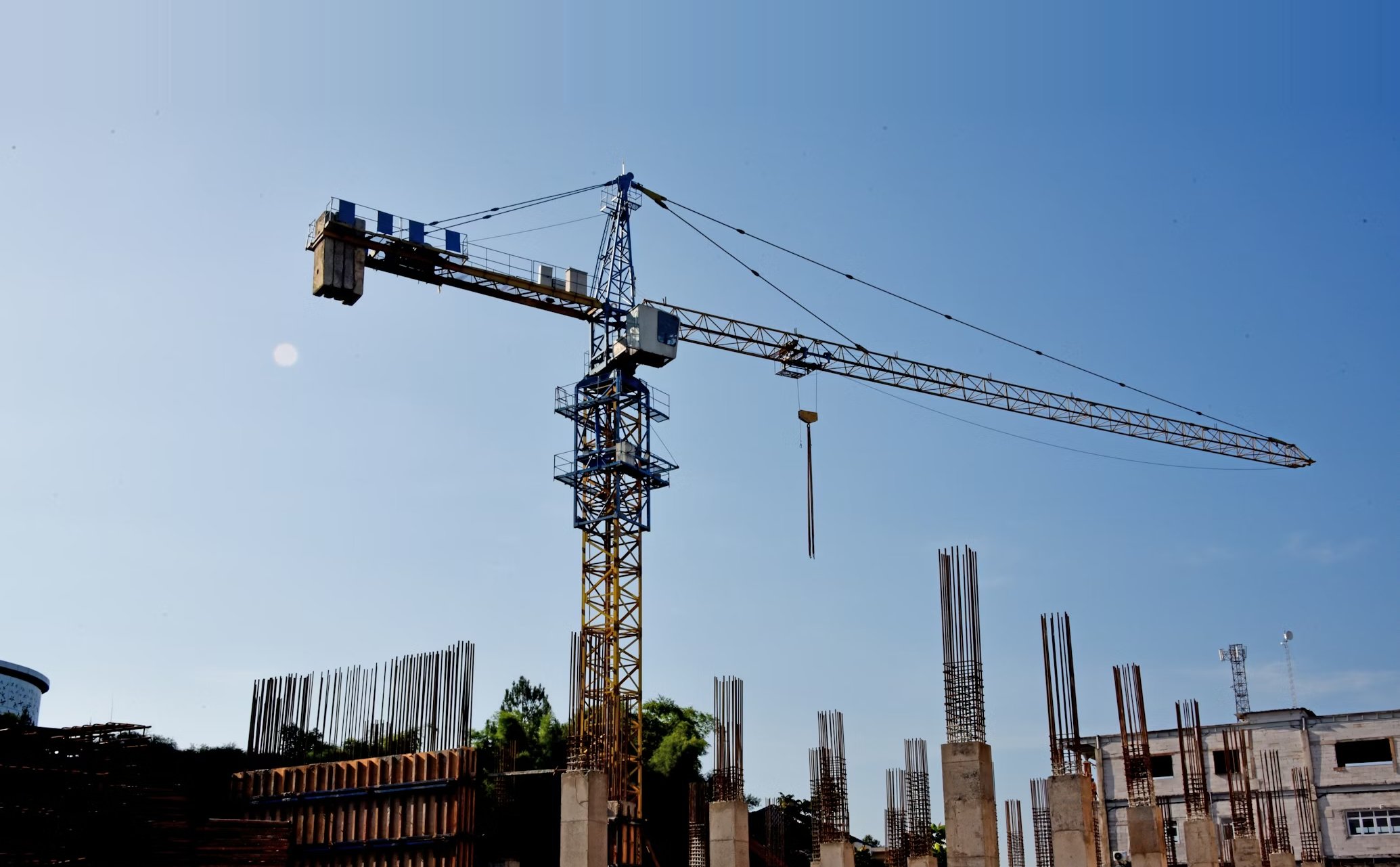 Construction site with tower crane and reinforced concrete columns — commercial building project in progress